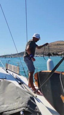 A man removes fenders from the side of a yacht before departure to sea. Vertical Video