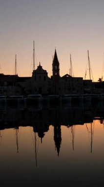 Silhouettes of yachts and the city against the backdrop of an early morning sunrise in Croatia. Vertical Video