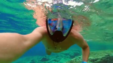 Maskeli ve şnorkelli bir adam. Suyun altında kendini filme çekiyor.