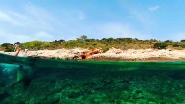 Tatili sırasında Adriyatik Denizi 'nin kayalık kıyılarında şnorkelle yüzen bir adam. Hırvatistan 'da güneşli bir yaz günü. Suya tekrar ve tekrar bak.