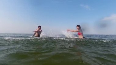 Genç bir çift okyanusta birbirlerine su sıçratır. Sahne ağır çekimde. Tatildeler ve su oyunları oynuyorlar..