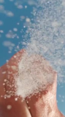 Kum, mavi gökyüzüne karşı ellerden kameraya akar. Yaz tatili kavramı. Dikey Video