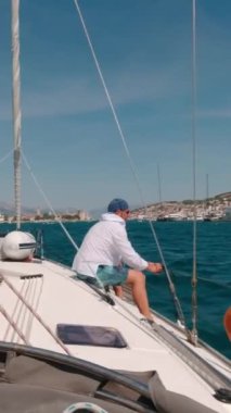 Bir adam limana girmeden önce bir yata çamurluk bağlar. Dikey Video