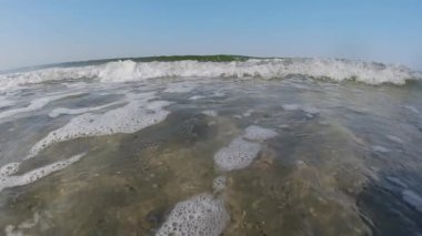 Bir deniz dalgası kameraya doğru hareket eder ve onu tamamen sular altında bırakır. Ağır çekim. Deniz Burnu. 