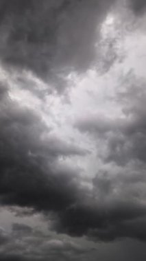 Gri fırtına bulutları gökyüzünde aralıklı olarak şimşekler çakar, fırtına, yağmur ve gök gürültüsü önceden haber verir. Dikey video.