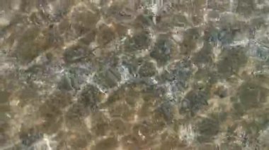 Aydınlık bir yaz gününde, güneş ışınları sığ deniz dalgaları üzerinde ışıltılı yansımalar yaratır, yaz veya tatil konsepti için ideal.