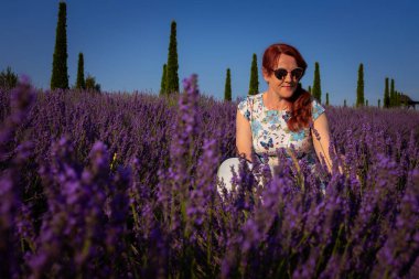 Bir kadın çiçek açan lavanta tarlasında huzurlu bir yaz sabahının tadını çıkarır, dinginliğin ve doğal güzelliğin özünü yakalar.