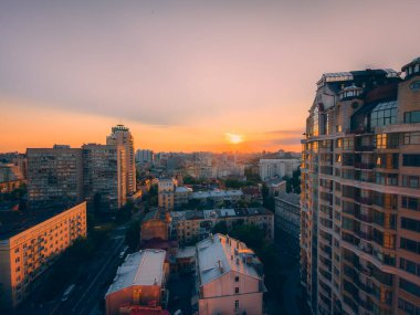 Gün batımında Ukrayna şehrinin göz kamaştırıcı hava manzarası. Altın saat ışığı şehri sıcak renklerle kaplıyor, modern mimari ve tarihi simgeler sergiliyor. Kyiv, Ukrayna