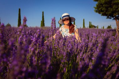 Zarif bir bayan, çiçeklerin canlı renkleri ve rahatlatıcı kokularıyla çevrili lavanta bahçesinde biraz dinlenir.