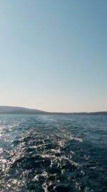 Güneşli bir yaz gününde, denizde hareket halindeki bir yatın suda bıraktığı iz. Deniz Burnu. Dikey Video