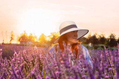 Batan güneş, lavanta tarlasında bir kadına sıcak bir ışık tutuyor. Kırsal kesimin huzurlu ve pitoresk doğasını vurguluyor.