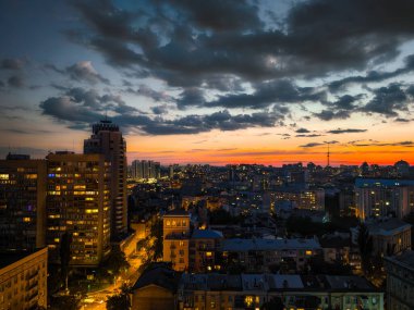Şehir gün batımında ışıldarken yukarıdan bir manzara... Kyiv, Ukrayna 'nın mavi gökyüzüne yol veren kara bulutlar...