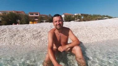 Hırvatistan 'da yaz sabahının erken saatlerinde halk plajının güzelliğini gösteren adam