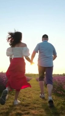 Güneş doğarken bir çift lavanta tarlasında el ele yürür. Sabahın dingin güzelliğinin tadını çıkarırlar. Ağır çekim. Dikey Video