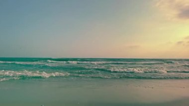 Bir yaz akşamının huzurlu atmosferinin tadını çıkarın. Kıyı şeridinde dalgalar yavaşça kırılıyor. Rahatlatıcı bir sahil kaçamağının özünü yakalıyor.