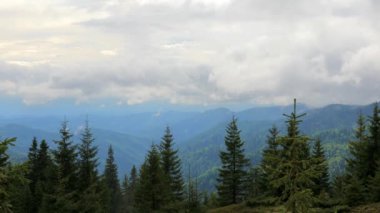 Bu resimli dağ manzarası dağlarda sürüklenen bulutları gösteriyor, zirvelerin ihtişamını vurguluyor.
