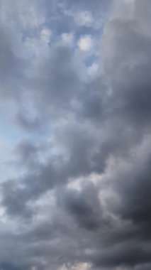 Geceleyin hareket eden gri bulutları gösteren, mavi gökyüzünü ve yukarıdaki beyaz bulutları kaplayan dikey hızlandırılmış bir video.