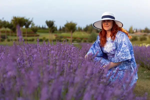 Huzurlu bir anda yakalanan, lavanta tarlasında bir kadın, çevresindeki sakinliğin ve güzelliğin tadını çıkarıyor, rahatlığı ve doğal cazibeyi simgeliyor.