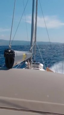 Yat gezisi ve deniz maceraları. Yat güneşli bir günde ufka doğru yarışıyor. Dikey Video
