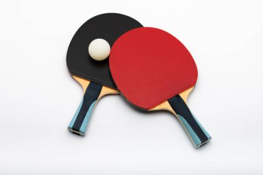 Stratejik olarak yerleştirilmiş beyaz topla kesişen siyah ve kırmızı profesyonel raketlerle modern masa tenisi ekipmanları, dinamik spor kompozisyonu sergiliyor.