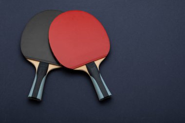 Karşıt siyah ve kırmızı kauçuk yüzey ve ergonomik kulplarla donanmanın arka planına karşı tasarlanmış özel pin pon raketleri içeren minimalist kompozisyon