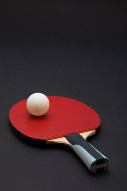 Turnuva derecesinde bir ping pong raketinin yakın çekim stüdyosu, dokulu kırmızı kauçuk yüzey, ergonomik ahşap saplı mavi aksanlı ve minimalist ayarlarda düzenlenmiş beyaz top.