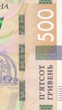 500 UAH banknotunun sağ tarafına odaklanan dikey video, ayrıntılı makro yakınlaştırma hareketi yoluyla gösterilen banknot numaraları, güvenlik unsurları ve koruyucu desenler