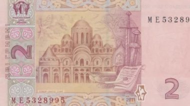Ukrayna 2 Hryvnia 'nın ters tarafının dinamik görüntüsü, tam banknottan Ruska Pravda parşömenine ve ortaçağ mührüne, antik Ukrayna yasal mirasını temsil eden ayrıntılı yakın plan çekimine zum yapıyor.