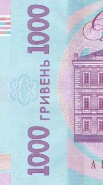 1000 UAH banknotunun sol bölümünün dikey yakın plan görüntüsü. Holografik detaylarla birlikte banknotlar, dalga desenli güvenlik unsurları ve mavi tonlarda koruyucu özellikler içeriyor.