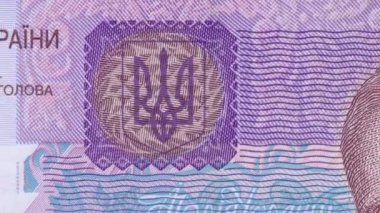 50 Hryvnia banknot görünümünü tamamlamak için Ukrayna milli mızrak ambleminin detaylı görünümünden dinamik olarak uzaklaşma, karmaşık koruyucu unsurlar ve Hruşevsky portresi