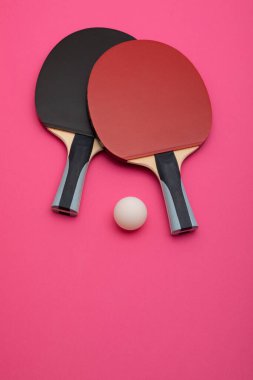Siyah ve kırmızı renkli profesyonel pinpon raketlerinin minimalist kompozisyonu, kaliteli kauçuk yüzeyler ve ergonomik saplar, canlı pembe arka plana karşı şekillendirilmiş