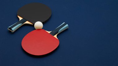 Turnuva derecesinde masa tenisi raketleri, zıt siyah ve kırmızı yüzeyler, kaliteli ahşap saplar ve derin donanma arka planına karşı tasarlanmış rekabet topu.