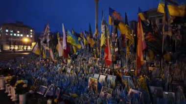 Kyiv, Ukrayna - 25 Aralık 2024: Kyiv Meydan 'daki şehit askerlerin gece vakti bayrakları, portreleri ve çiçeklerle onurlandırılması, Ukrayna' nın savaş sırasındaki kederi ve dayanıklılığını simgeliyor.