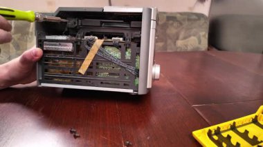 Tahta bir masada tamir edilmek üzere parçalanmış bir stereo sistem. Görünür kablolar ve elektronik bileşenler bakım süreci sırasında araçlarla elle çalıştırılıyor