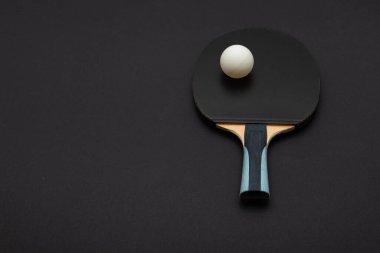 Siyah, turnuva sınıfı, kauçuk yüzeyi ve ergonomik ahşap saplı bir masa tenisi raketi içeren zarif bir stüdyo kompozisyonu.