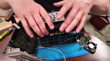 Görünür devre kartlarına, kablolara, soğutma vantilatörüne ve bir atölyede tamir edilen veya modifiye edilen bir masa üzerindeki ısıtıcıya sahip parçalanmış bir elektronik cihaz.