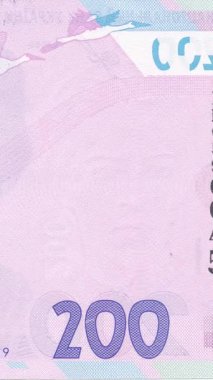 Ukrayna 200 Hryvnia banknotunun detaylı makro fotoğrafçılığı, mavi ve pembe-mor renk düzeninde holografik desenler içeren banknotlar ve güvenlik elemanlarına odaklanıyor