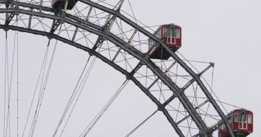 Prater Parkı 'ndaki ikonik Viyana Dönme Dolabı bulutlu gökyüzünün altında kırmızı gondolları ve çelik çerçevesiyle duruyor. 1897 'de Viyana' da inşa edilmiş tarihi bir eser.