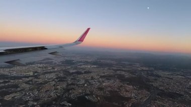 Lizbon 'un ikonik 25 Nisan Köprüsü ve gün batımında Tagus Nehri' ne yaklaşan uçak penceresinden görülen kral heykeli ile nefes kesici hava manzarası.