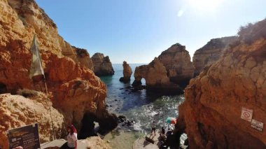 Lagos, Portekiz - 13 Ekim 2019: Portekiz, Lagos yakınlarındaki Ponta da Piedade 'de olağanüstü doğal kemer oluşumu, kristal berrak turkuaz suları çevreleyen dramatik altın kireçtaşı kayalıkları, yerel balıkçıların tekne turları sunduğu
