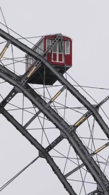 Prater Parkı 'ndaki ikonik Viyana Dönme Dolabı bulutlu gökyüzünün altında kırmızı gondolları ve çelik çerçevesiyle duruyor. 1897 'de Viyana' da inşa edilmiş tarihi bir eser.