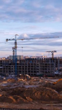 Şantiye zaman çizelgesinde, günbatımı aydınlatmalı dramatik bulutlara sahip konut inşaat iskeletine karşı heybetli kule vinci silueti yer alıyor. Sağdan sola kamera hareketi, akşam ışığında yıkanan toprak ve materyalleri yakalıyor.