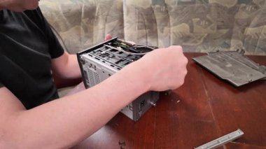  Bir adam, bir DIY donanım bakım süreci sırasında ahşap bir masa üzerinde görünür elektronik bileşenler ve kablolar ile bir bilgisayar sistemi ünitesi montajı veya onarımı üzerinde çalışır.