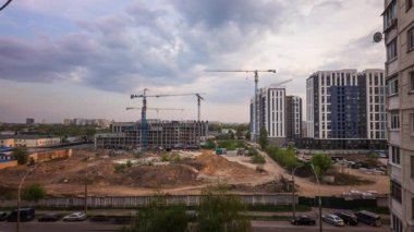 Gündüz vakti statik ve geniş kamera hareketiyle çekilen vinçleri, makineleri, kiri ve kentsel silueti olan modern bir apartman inşaatının zaman çizelgesi.