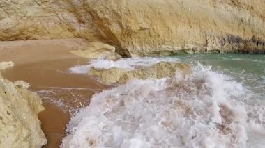 Güçlü dalgalar Portekiz 'in ünlü Praia de Benagil kıyılarına çarpıyor çarpıcı kaya oluşumları ve dünyaca ünlü Benagil Mağarası yakınlarındaki kristal berrak turkuaz sularıyla.