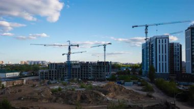 Büyüleyici zaman çizelgesi meşgul inşaat alanının üzerinde büyüleyici bulut hareketini yakalıyor altın günbatımı ışığı kentsel ufuk çizgisine karşı yükselen apartman binalarını aydınlatırken dönen vinçler ve işçiler hareket halinde.
