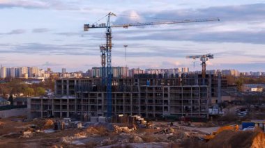 Kentsel gelişim zaman çizelgesi, yüksek inşaat vinci ve pembe bulutlu dramatik alacakaranlık gökyüzüne karşı beton iskelet. Zorlama etkisi, gelişmekte olan şehir bölgesindeki modern konut binasının mimari ilerlemesini vurguluyor