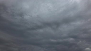 Kasvetli gökyüzünde hızla ilerleyen gri bulutların dramatik zaman atlaması. Akan fırtınalı oluşumları olan güzel atmosferik bulutlar. Hava fenomenleri, çevre konuları ya da dramatik doğa sahneleri için mükemmel bir sinemasal arka plan