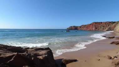 Portekiz 'in kıyı yolu açık mavi gökyüzünün altında güneşli bir günde okyanus manzarasına giden park edilmiş araçlarla dolu.