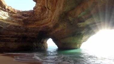 Portekiz 'in Algarve bölgesindeki ünlü Benagil Deniz Mağarası' nın nefes kesen iç manzarasında doğal kaya kemeri, altın kum plajı ve güneş ışığıyla aydınlatılan kristal berraklığında turkuaz sular yer alıyor.